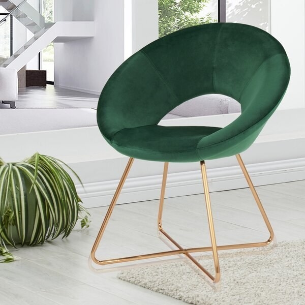 A green round chair with a hole in the center and gold legs that cross at the bottom 