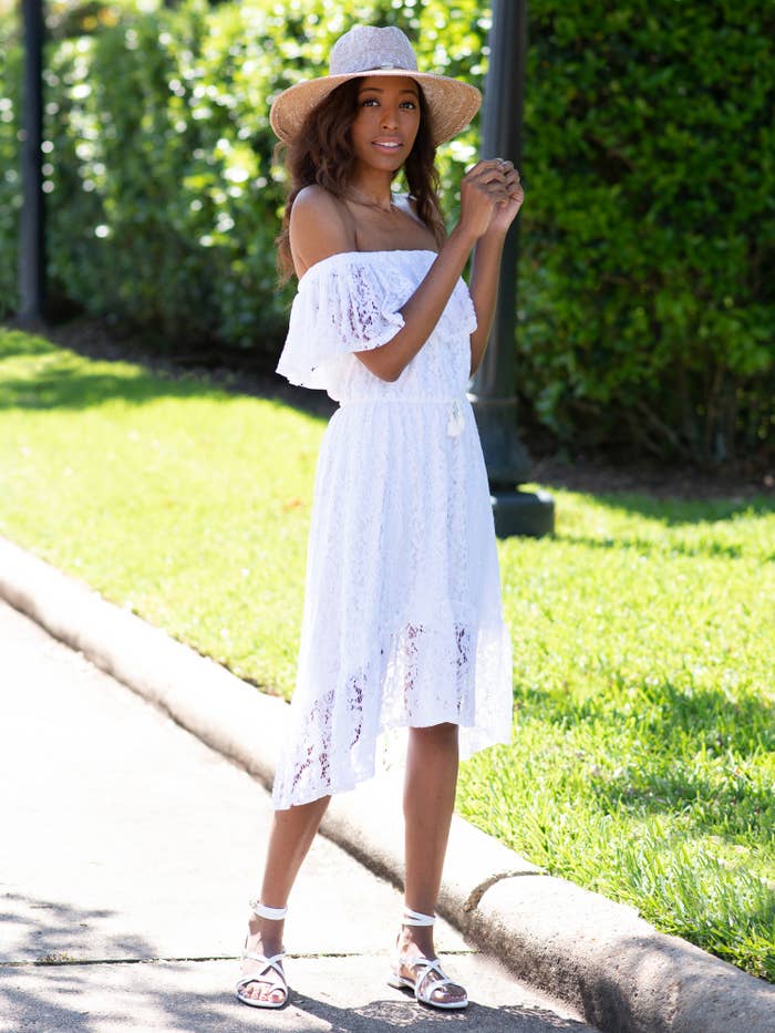 a model in a white off the shoulder lace dress