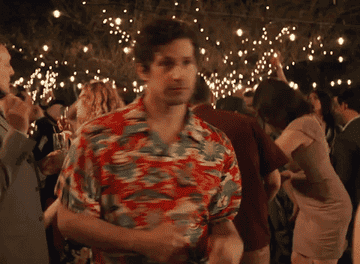 A gif of Andy Samberg in Palm Springs dancing in a tropical button up
