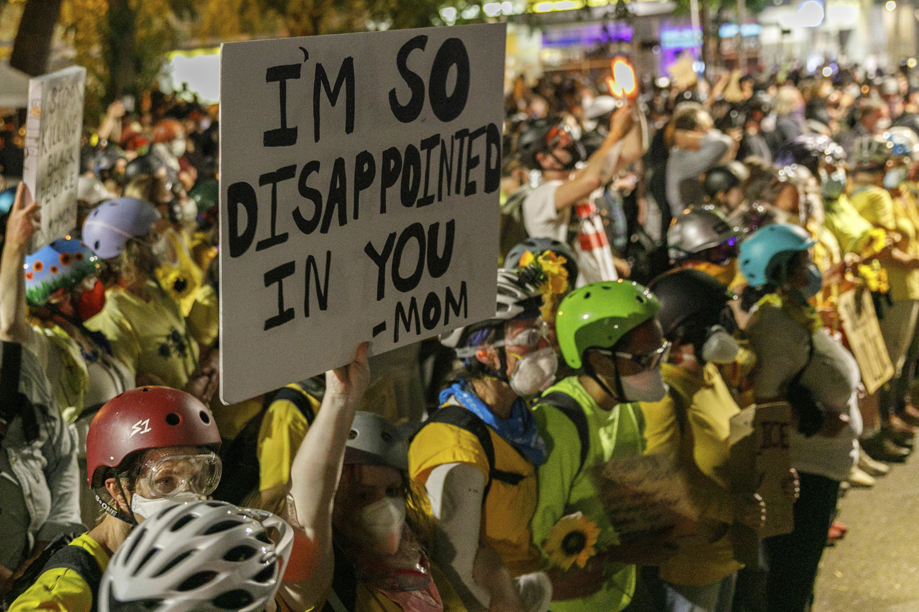 A mother carrying a sign that says &quot;I&#x27;m so disappointed in you — mom&quot; marches with other demonstrators in Portland. 