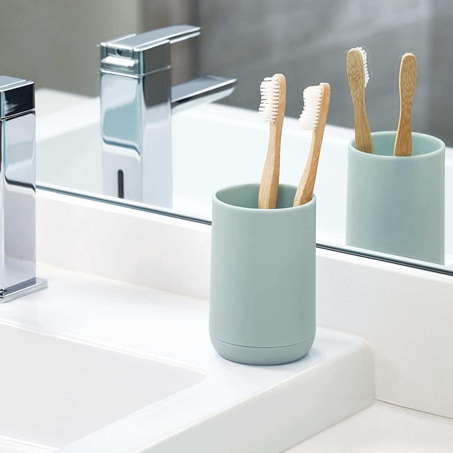 The toothbrush holder on a counter with two bamboo toothbrushes in it