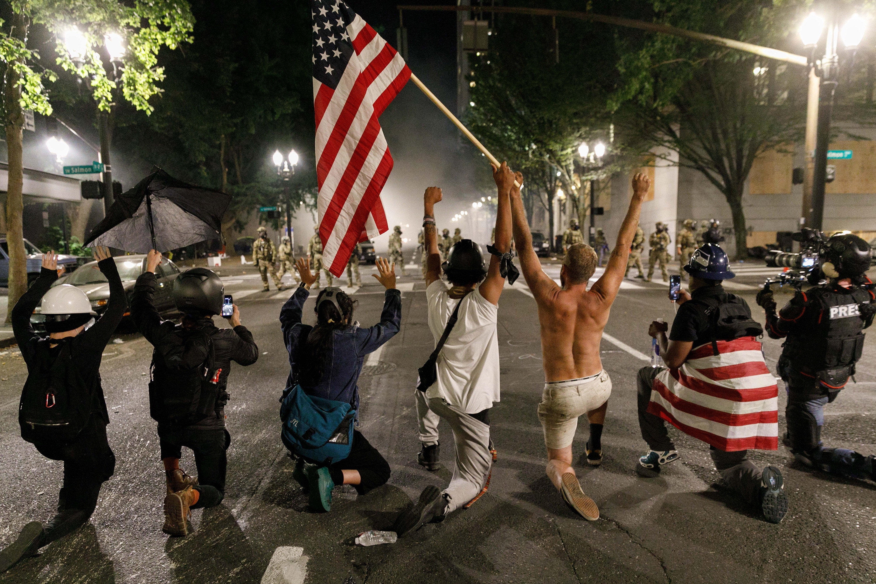 People kneel in front of federal marshals during a protest in Portland