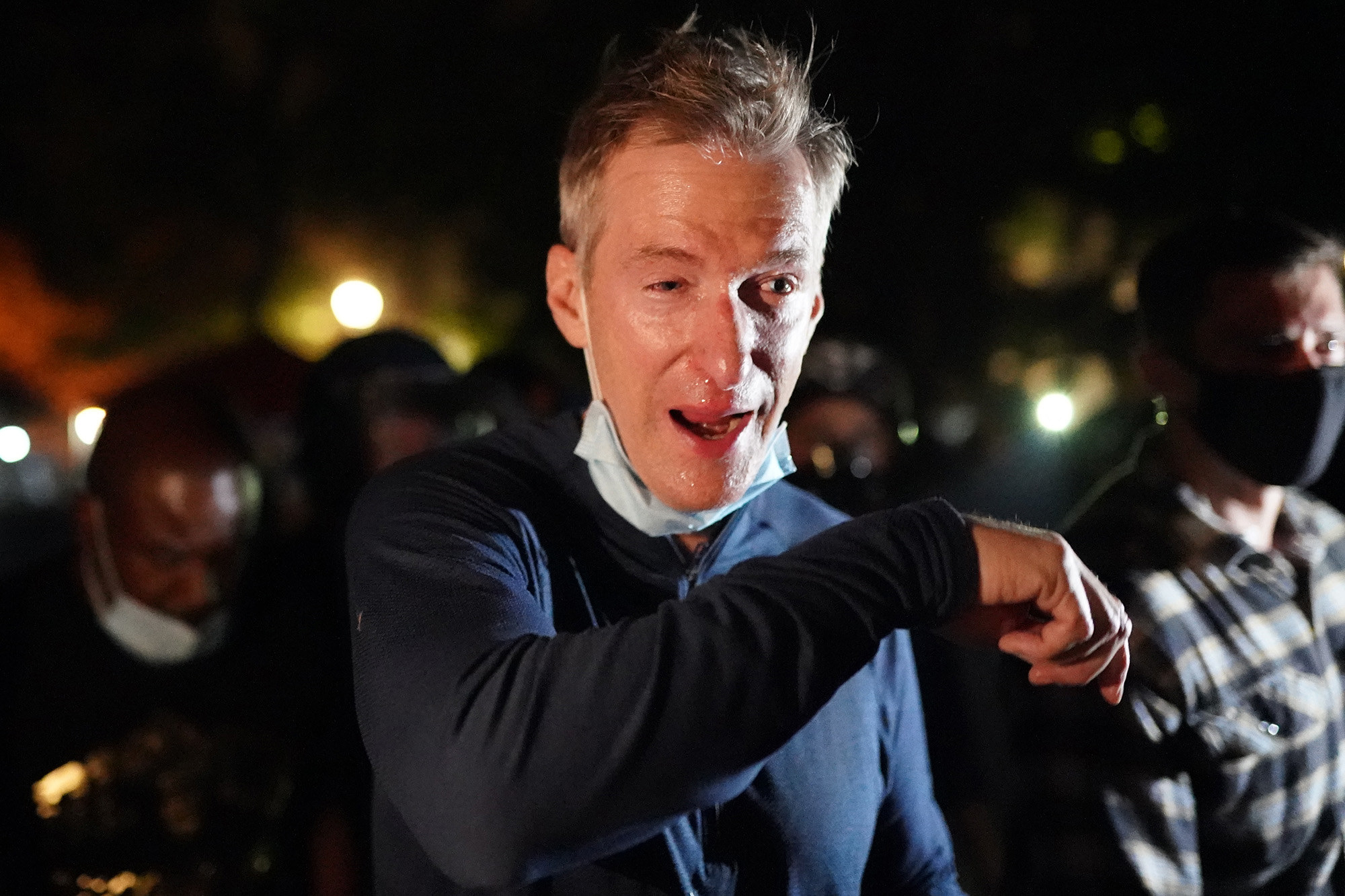 Portland Mayor Ted Wheeler reacts after being exposed to tear gas. His eyes water and he lefts his arm to his face