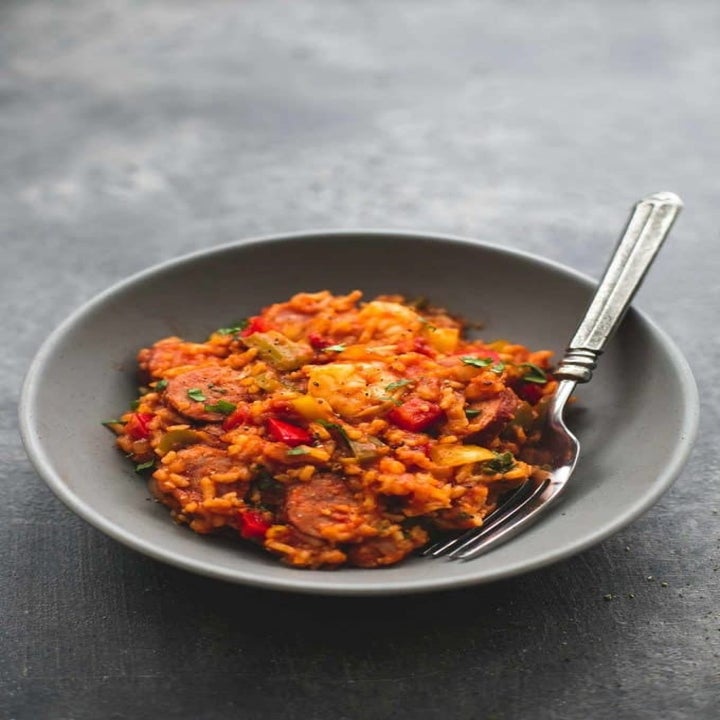 A bowl of jambalaya with a fork in it.