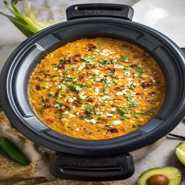 Creamy Mexican street corn chowder in a crock pot with bacon, onion and cheese.