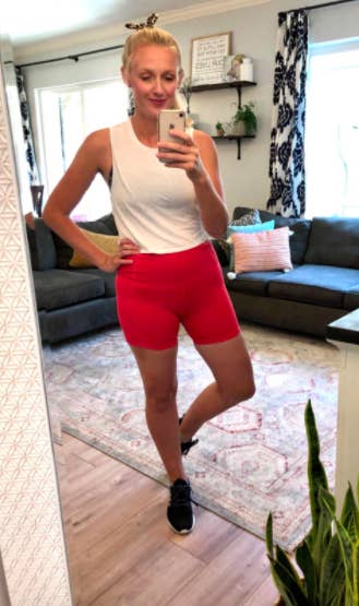 Reviewer wears white tank top with pink high-rise bike shorts while posing in front of a mirror
