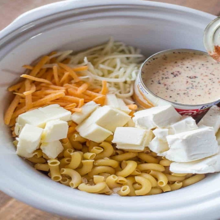 Elbow noodles, cream cheese, shredded cheese, and cream of mushroom soup in a slow cooker.