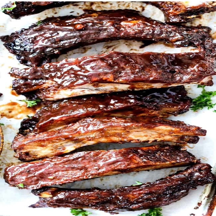 Sliced ribs on a cutting board, coated in juicy barbecue sauce. 