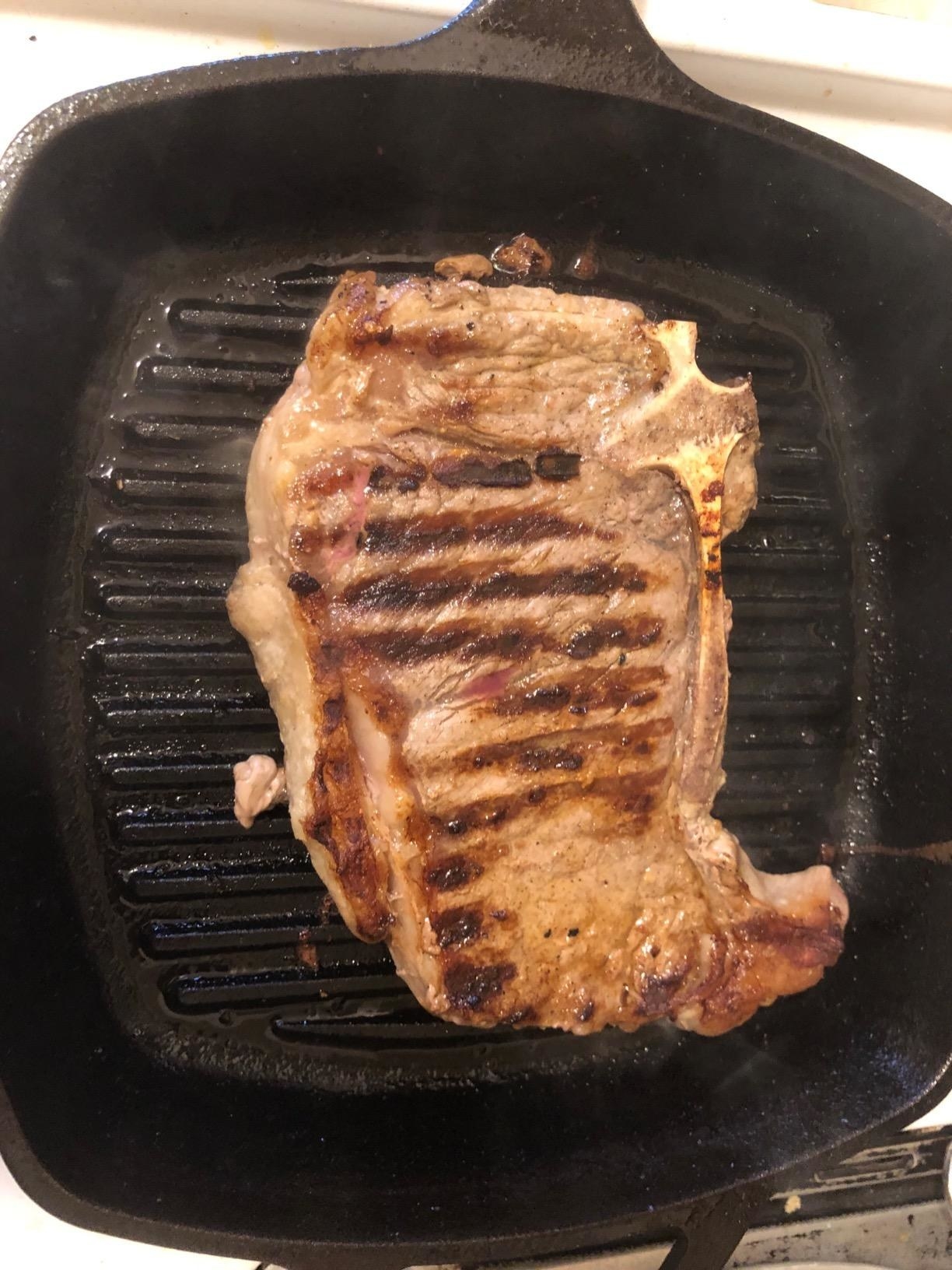 A reviewer cooking a steak in the pan, with grill marks