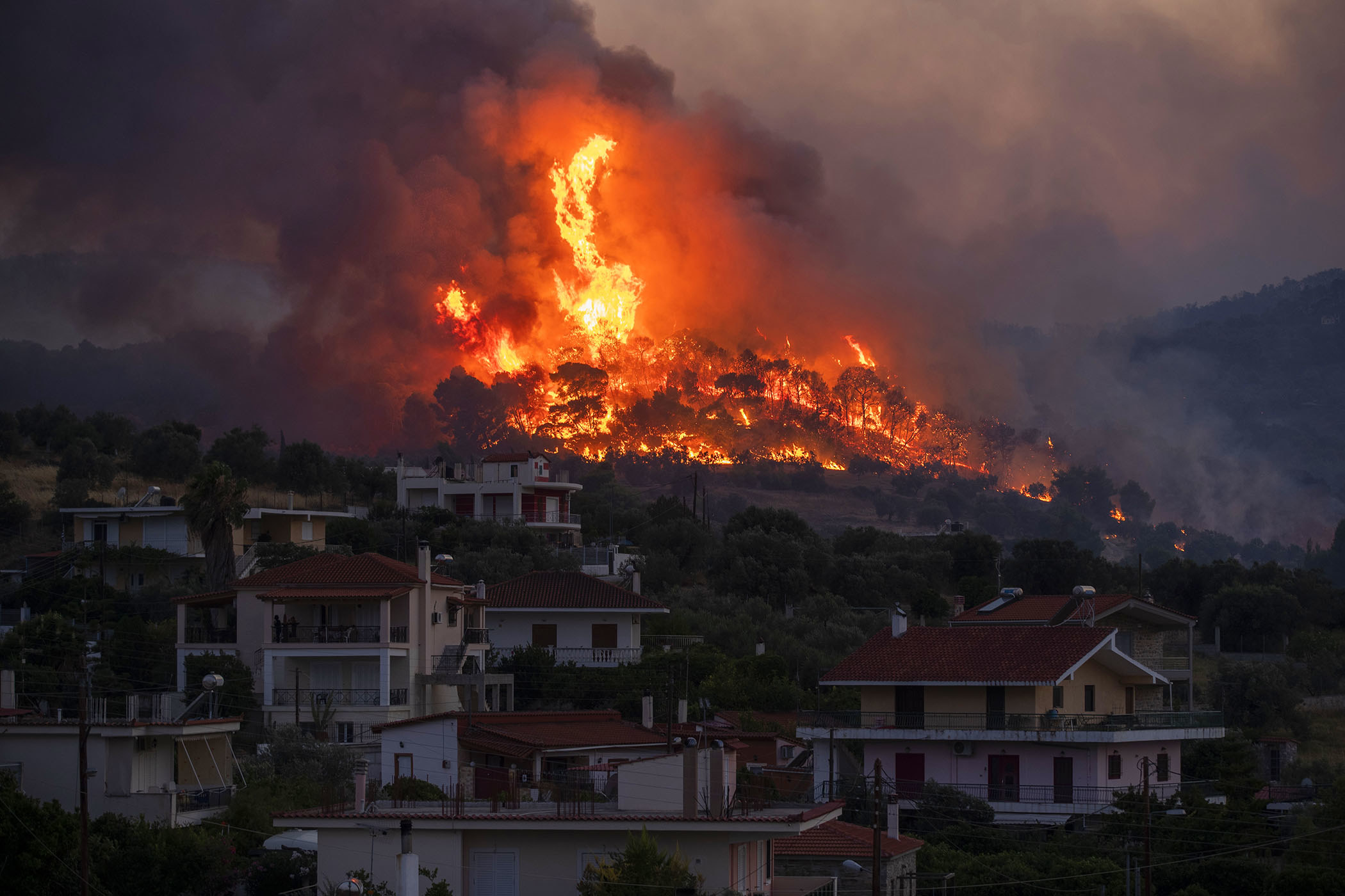 A fire blazes on a hill just behind a residential neighborhood