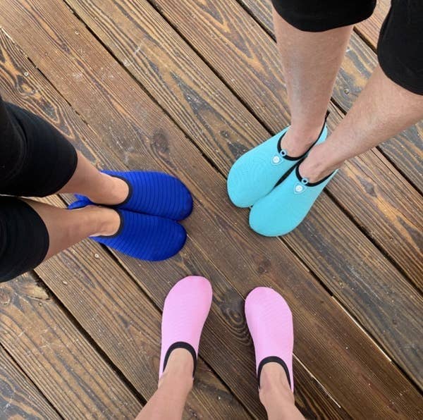 A reviewer photo of three people wearing the water shoes in light pink, blue, and turquoise