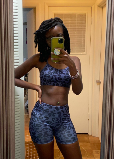 Reviewer wears blue leopard bra and bike shorts set while posing in front of a mirror