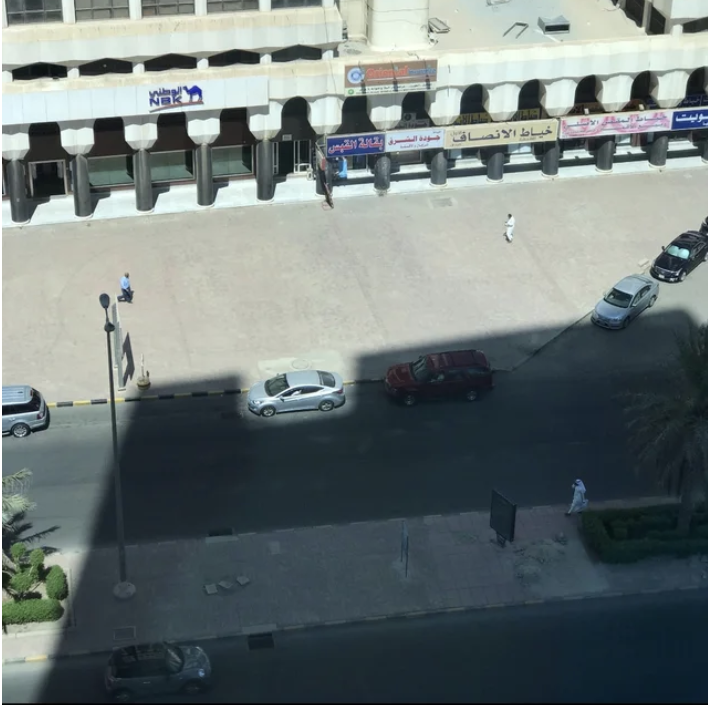 Shadows are everywhere except in one spot where sunlight perfectly frames a car