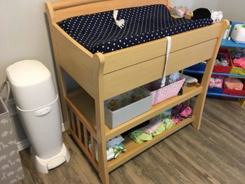 White Diaper Genie stood next to a baby's changing table for scale