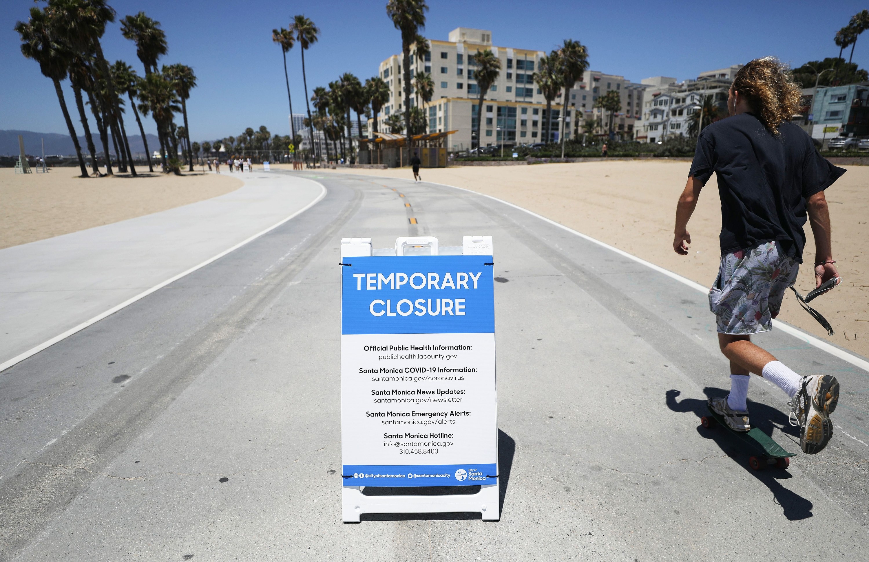 A man skates by a notice of the beach&#x27;s temporary closure