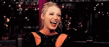 A GIF of Blake Lively wearing a black, sparkly dress, laughing