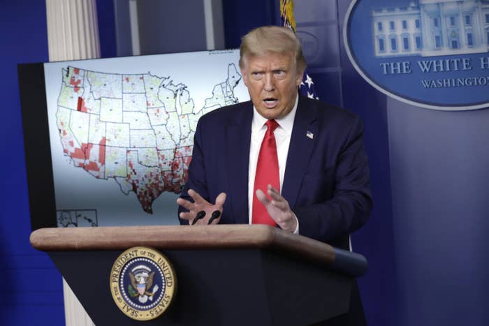 Trump at a podium in front of a map of the coronavirus outbreak in the United States