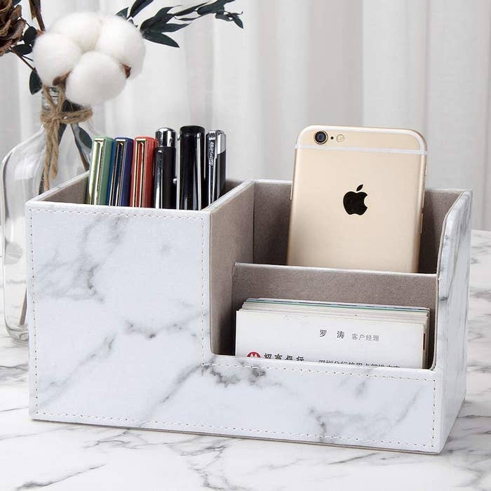 A desk organizer with pens, cards, and a phone inside