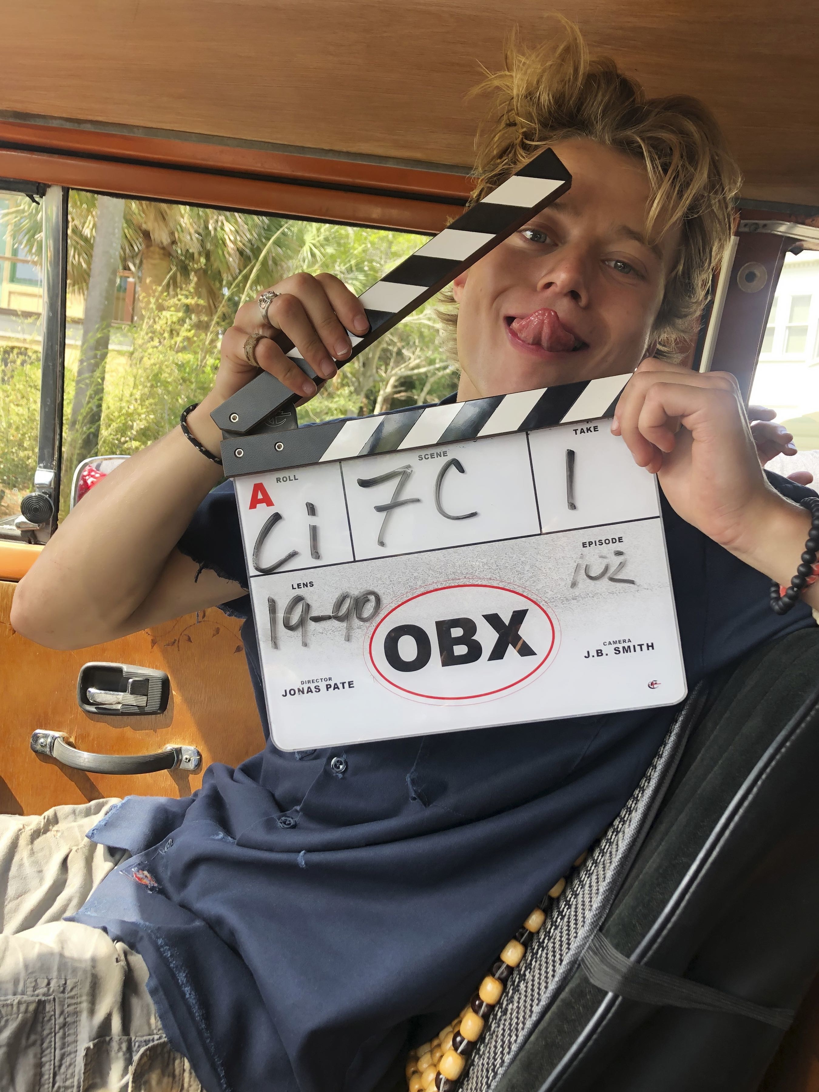 Rudy Pankow sticking his tongue out with a clapboard behind the scenes of Outer Banks