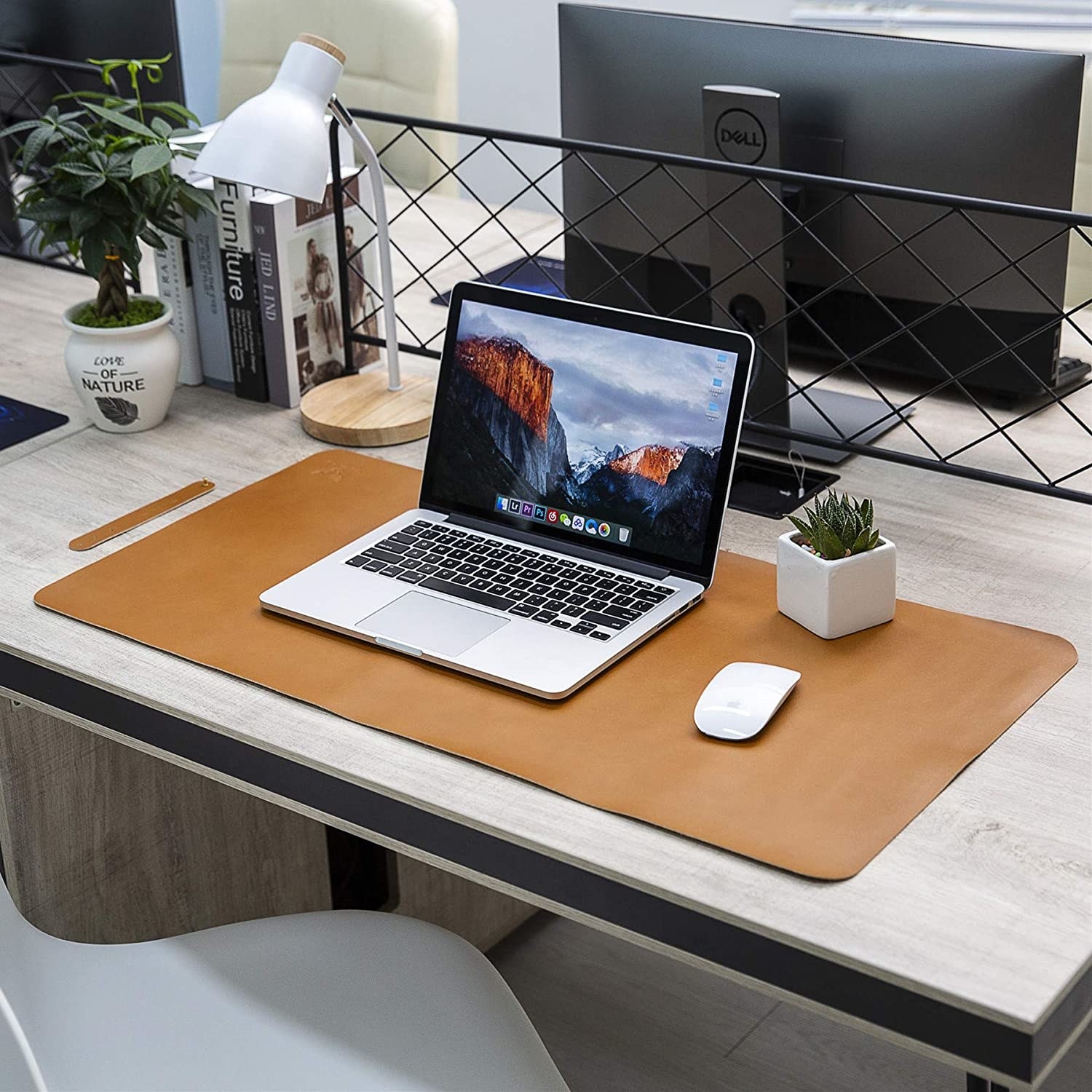 A desk with a laptop and mouse on it under a leathery rectangular mat