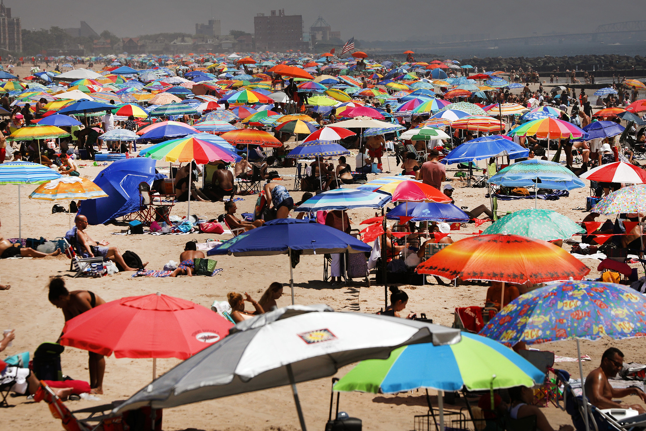 A crowded beach is filled with sunbathers and people lounging under umbrellas