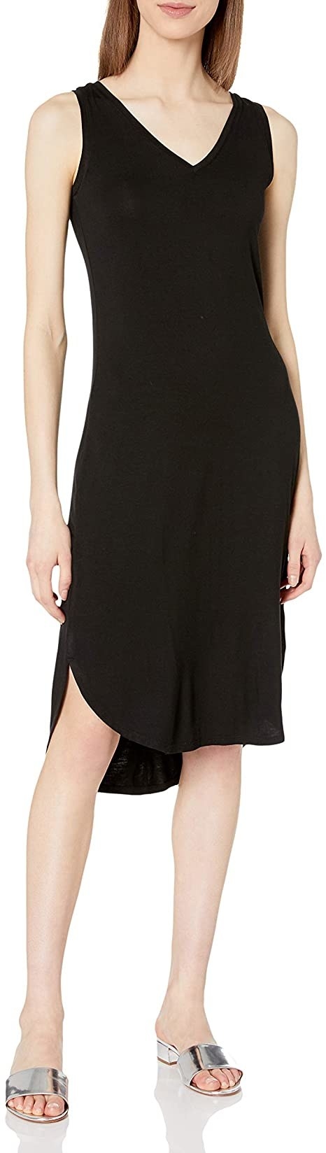 model wearing sleeveless V-neck black dress with curved hem that hits at the knee