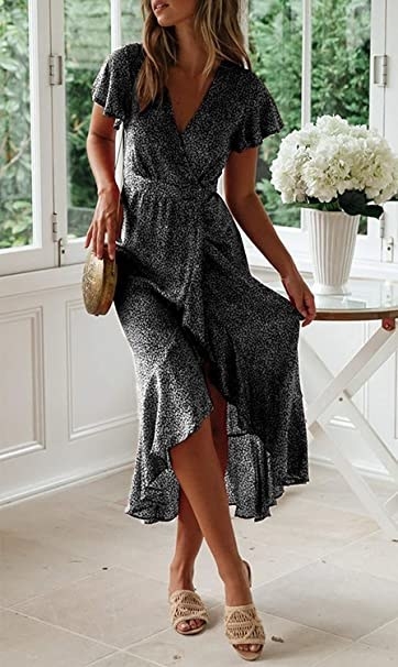 model wearing black dress with dainty white floral print on it in a wrap dress that hits just below the knee and with fluttery short sleeves
