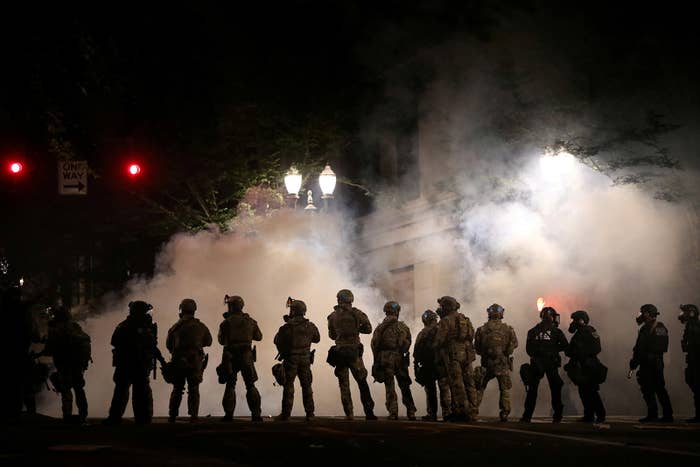 Silhouettes of a row federal officers standing on a street in Portland