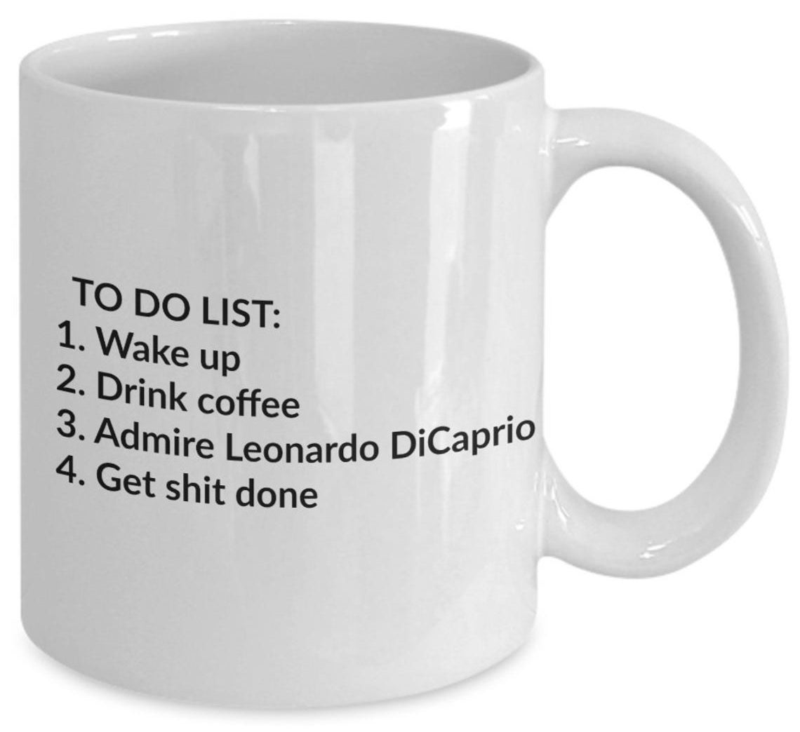 A white ceramic mug that reads, &quot;TO DO LIST: 1. Wake up 2. Drink coffee 3. Admire Leonardo DiCaprio 4. Get shit done&quot;