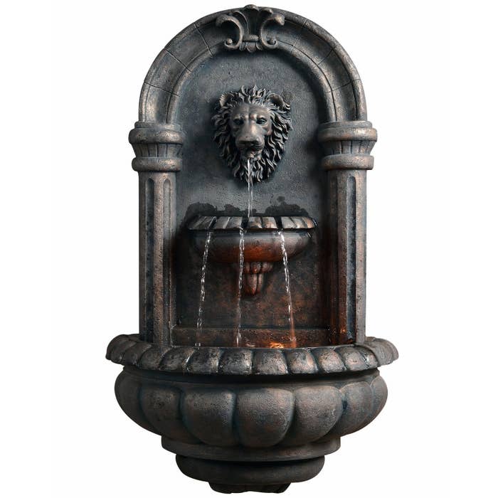 a stone fountain with water coming out of a lion's mouth