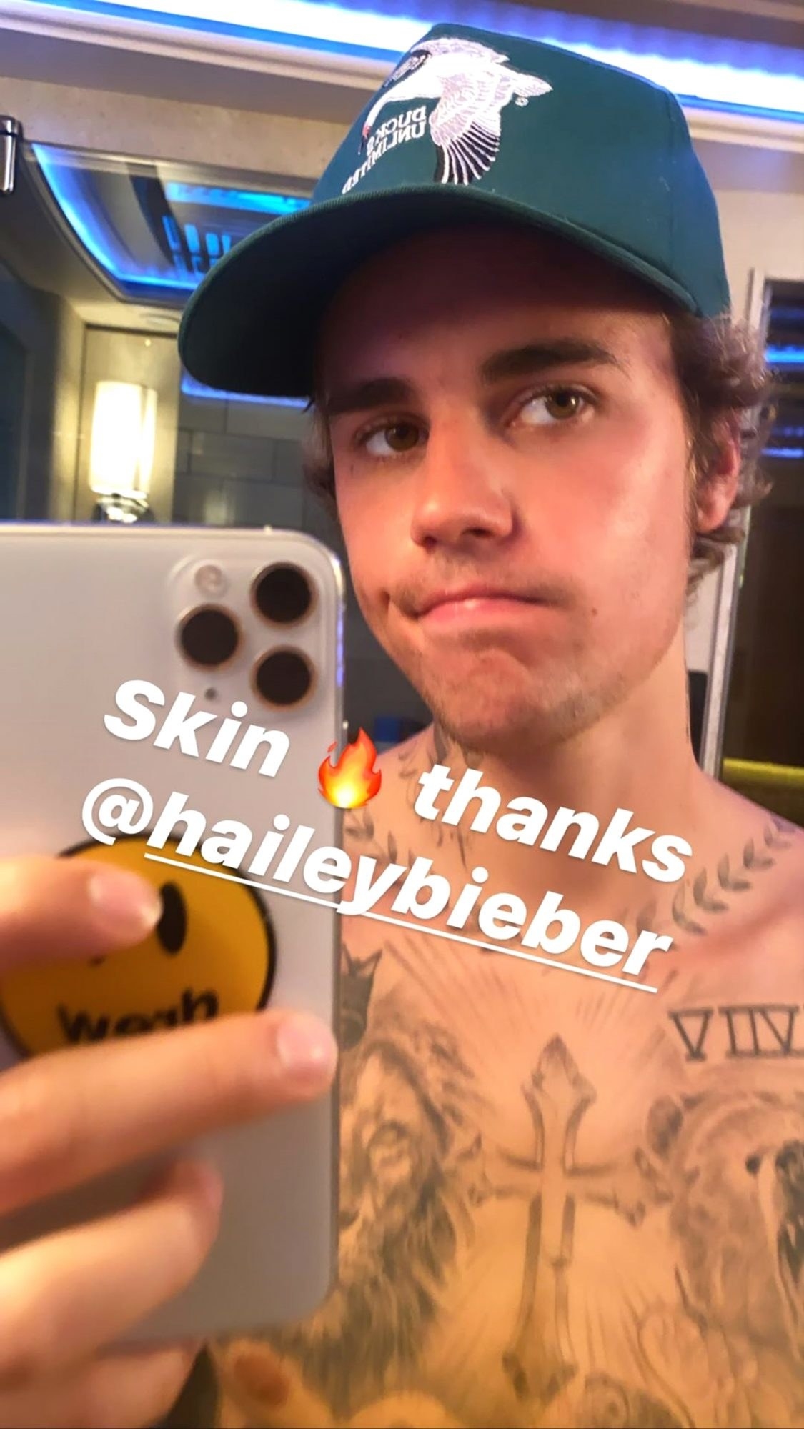 Justin Bieber holds his phone to take a selfie of his acne-free skin in the mirror