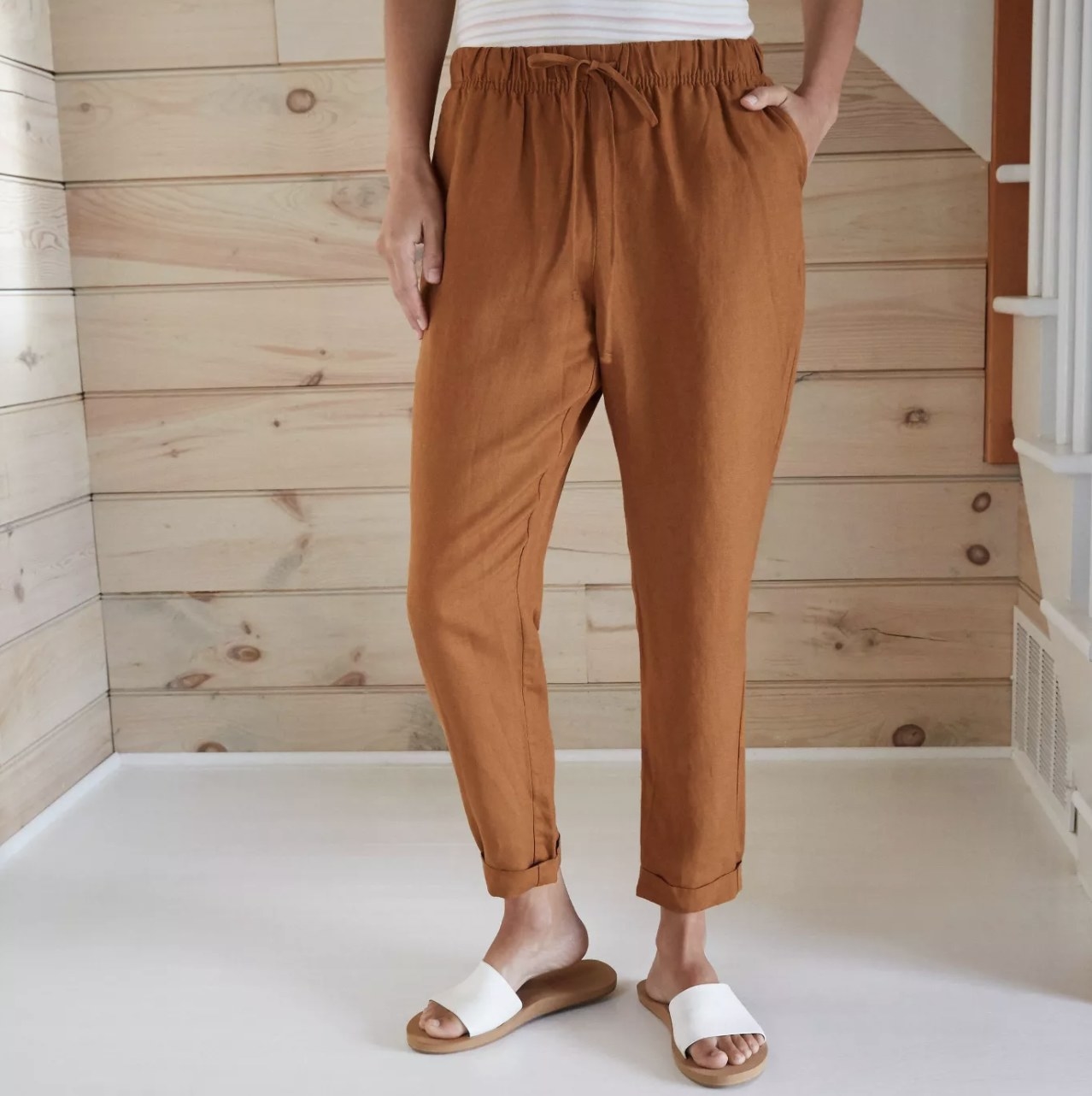 A model wearing dark orange pants that hit above the ankle