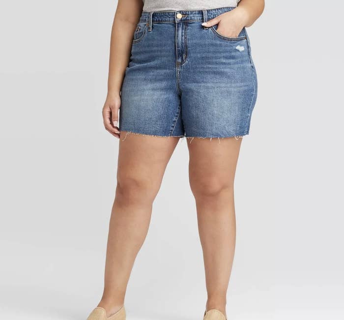 A model wearing a pair of jean shorts that hit mid-thigh