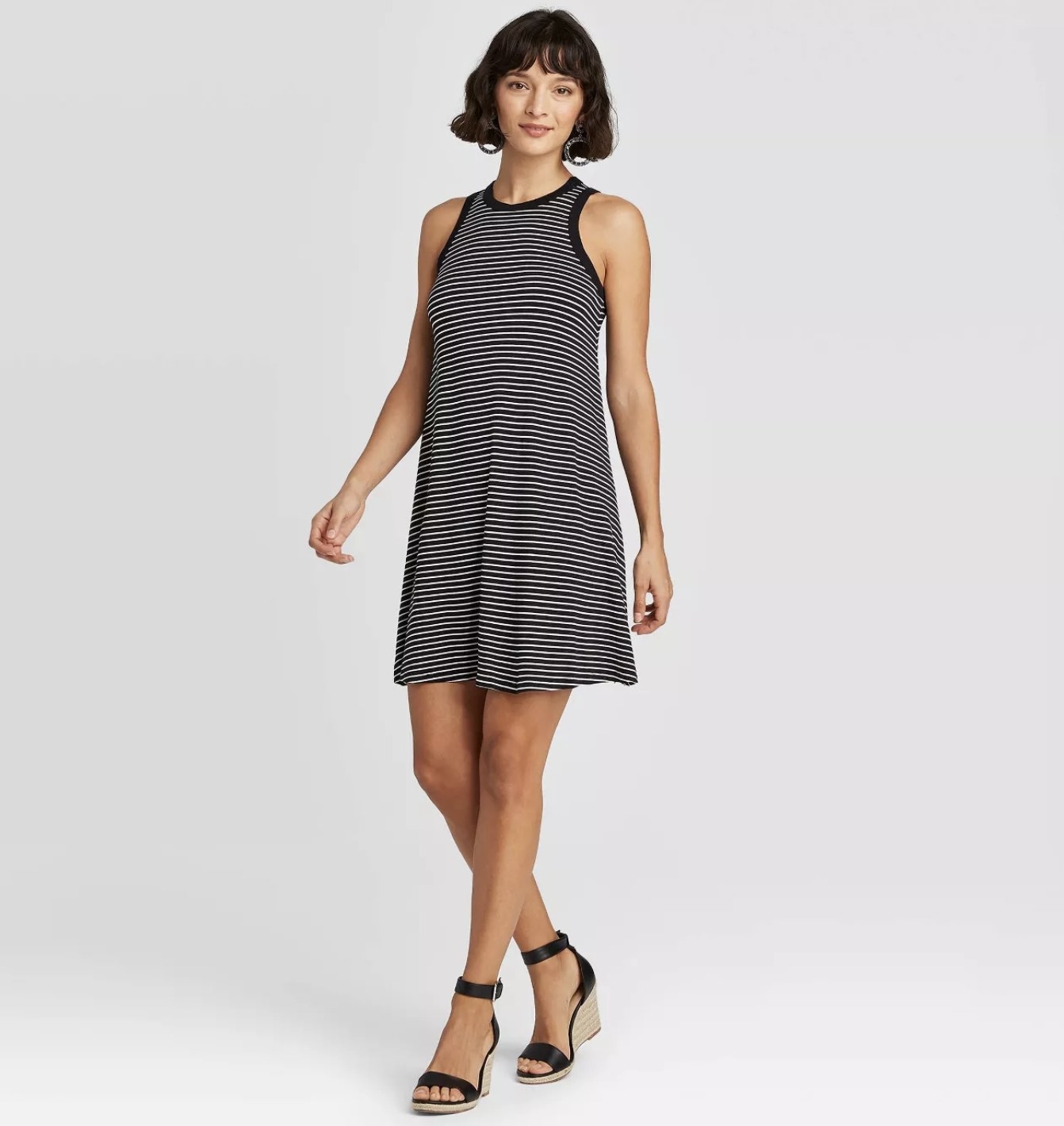A model wearing a black and white horizontal striped dress that hits mid thigh