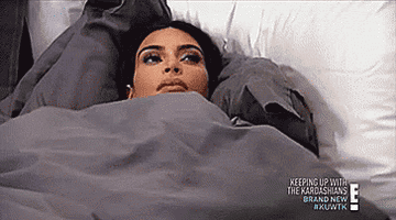 Kim Kardashian lying underneath her sheets, staring at the ceiling.