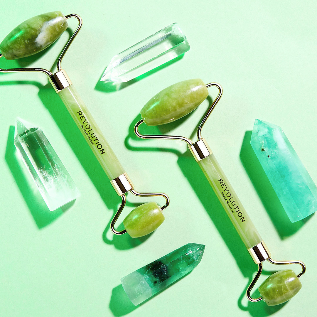 A flatlay of two jade rollers next to loose jade stones