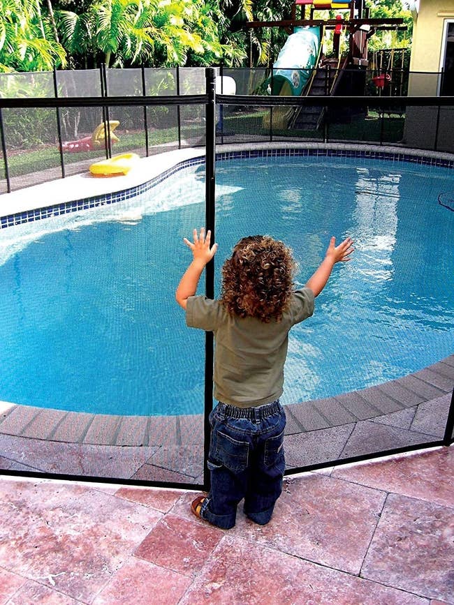 A child pushing against the mesh pool gate without being able to get through 