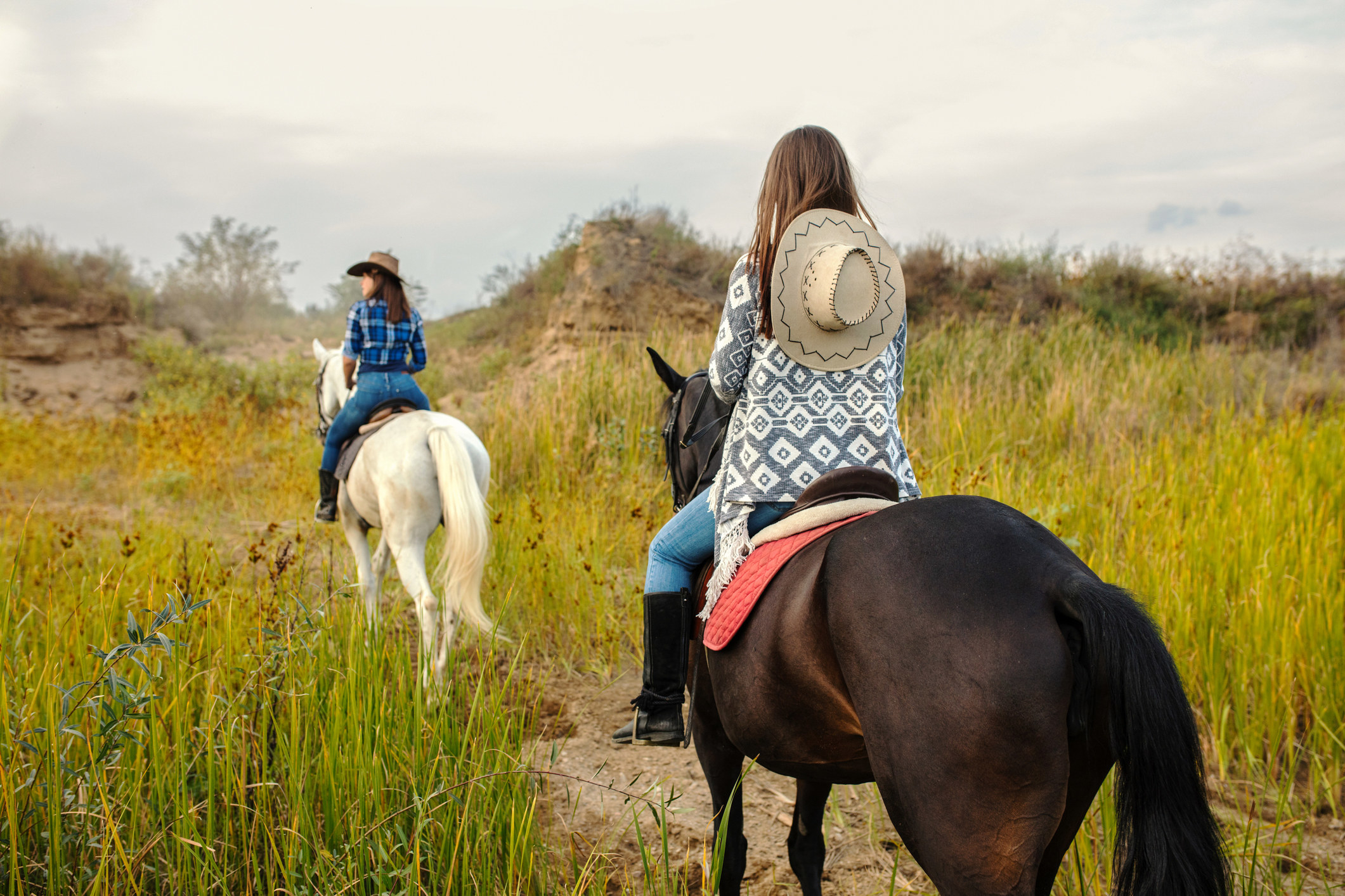 Two women on a trail ride with horses.