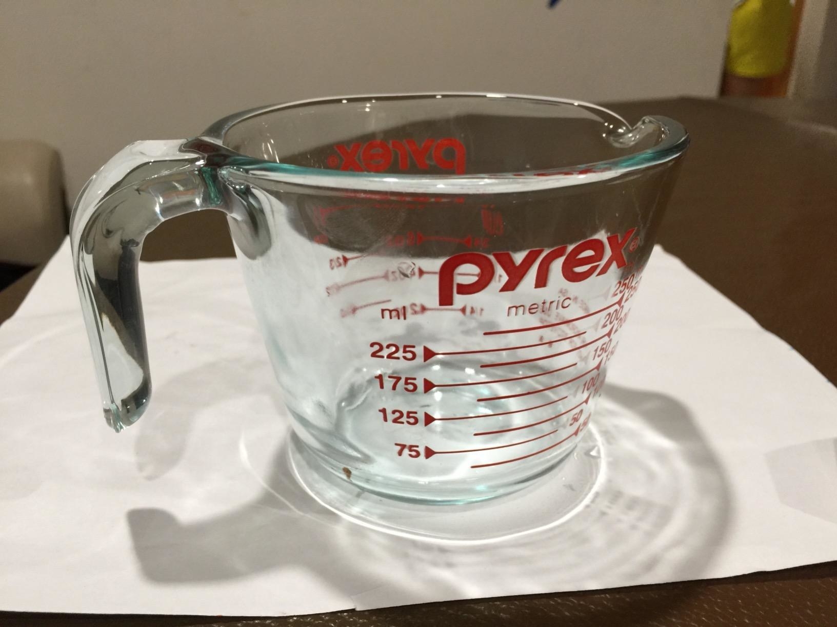 A reviewer showing the pyrex glass measuring cup, which measures up to one cup of liquid