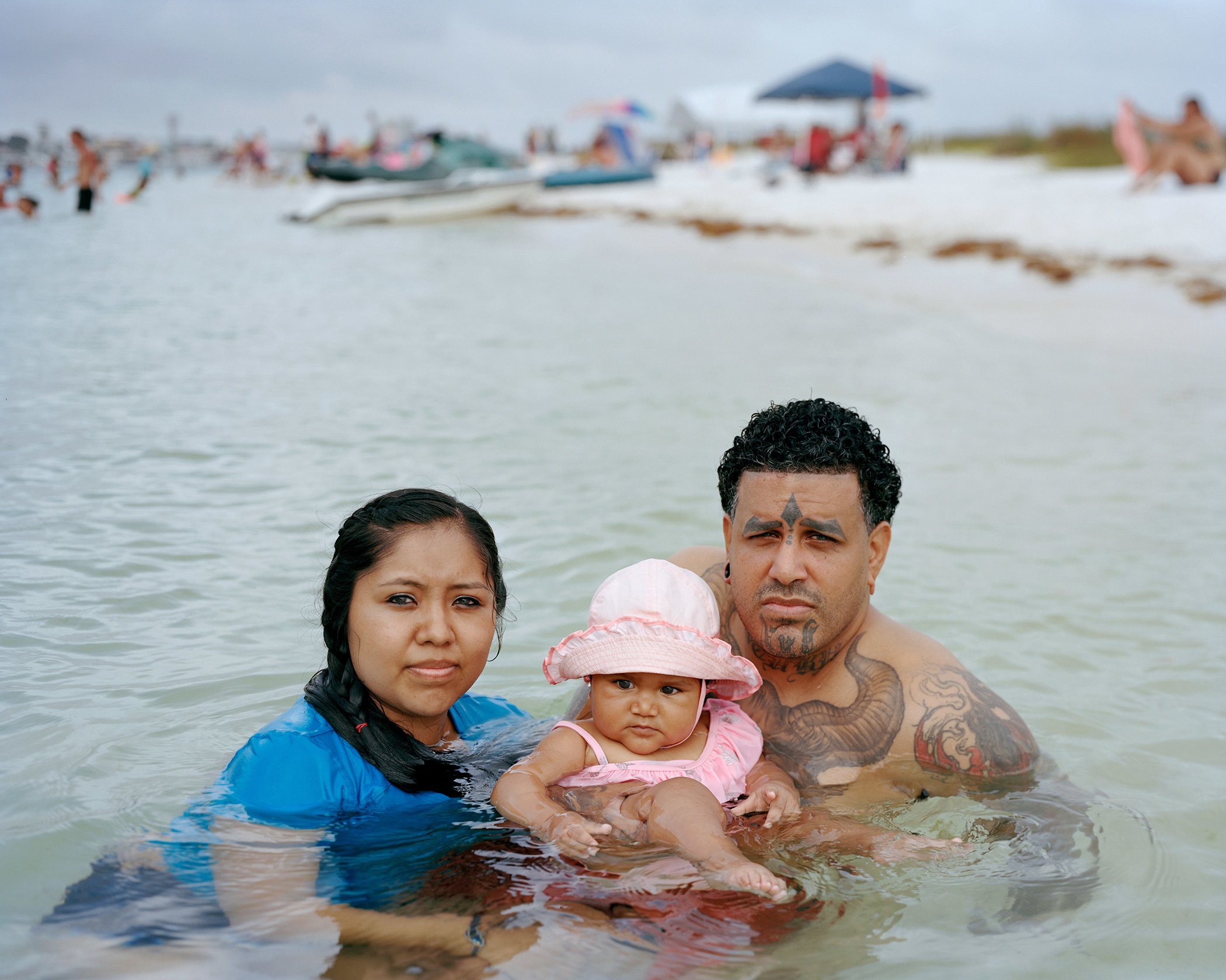 A couple and their baby girl swim in the shallow coastal waters of Florida