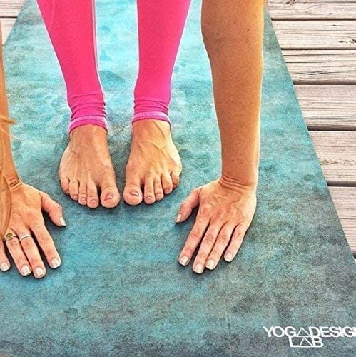 Close up of the mat with a texture to it and a model&#x27;s hands and feet on the mat
