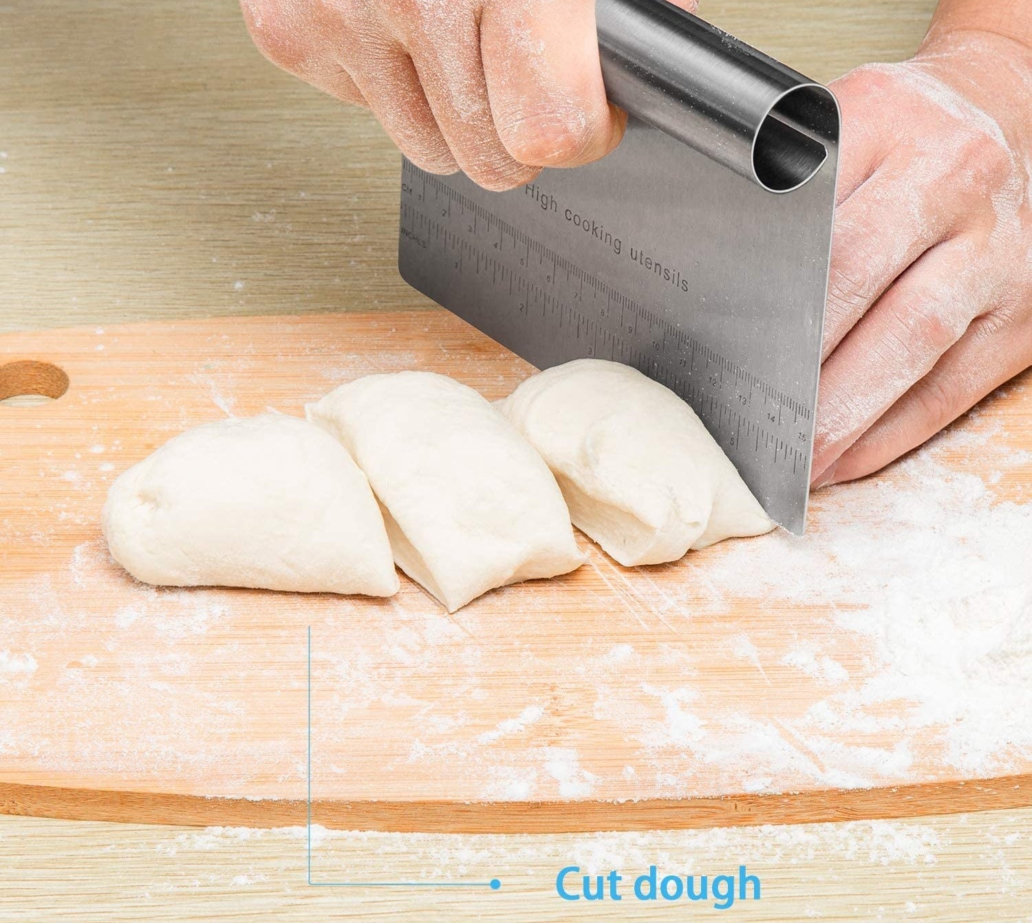 A person using the edge of the scraper to cut dough