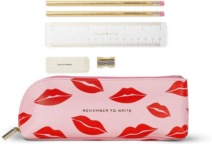 A small leather pencil case with two pencils, a ruler, an eraser, and a pencil sharpener beside it