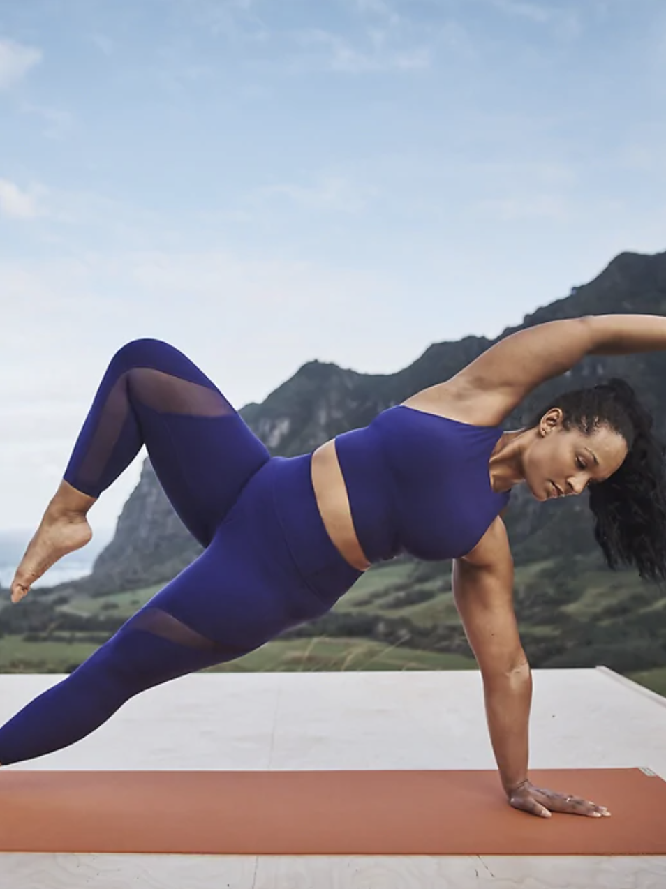 Model wearing the crop in bright blue while doing a side plank yoga pose