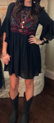 reviewer wearing the black dress with black cowboy boots