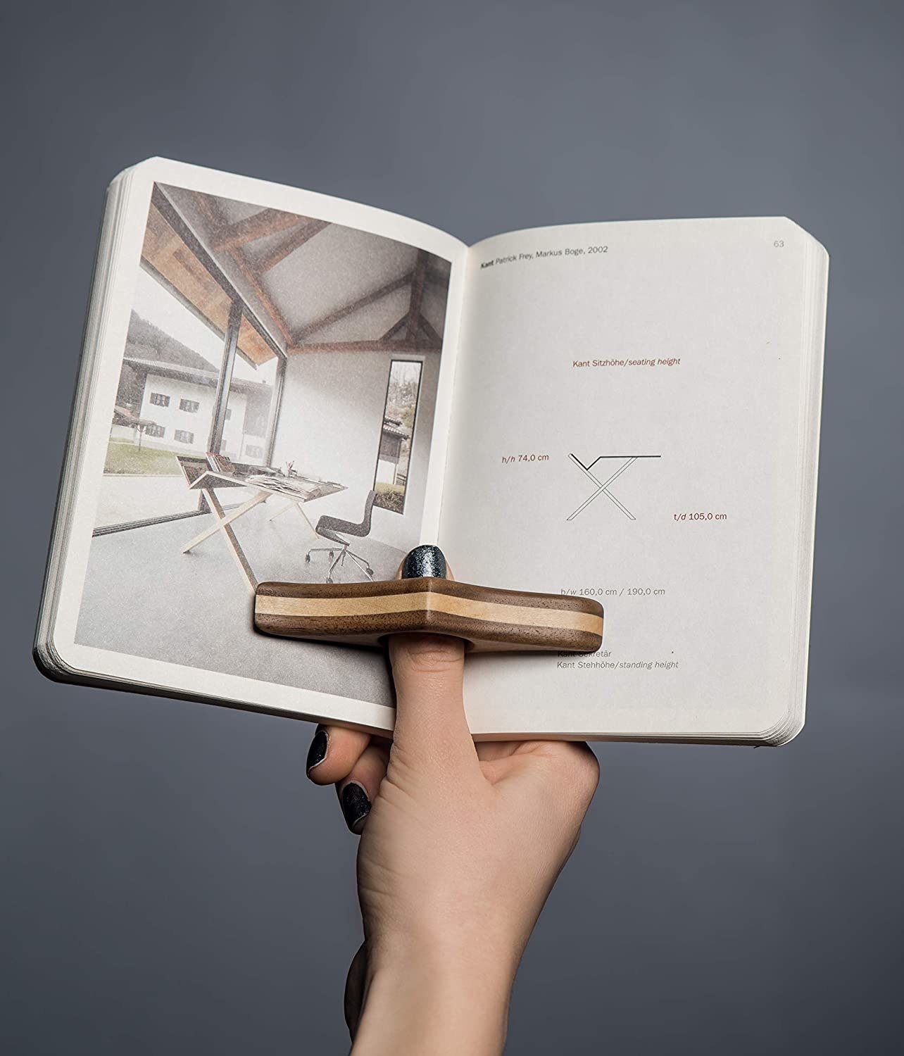 A hand using the tool to prop open a book