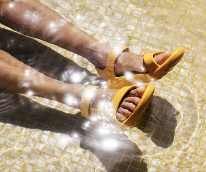 Model wearing the yellow sandals in a pool of water
