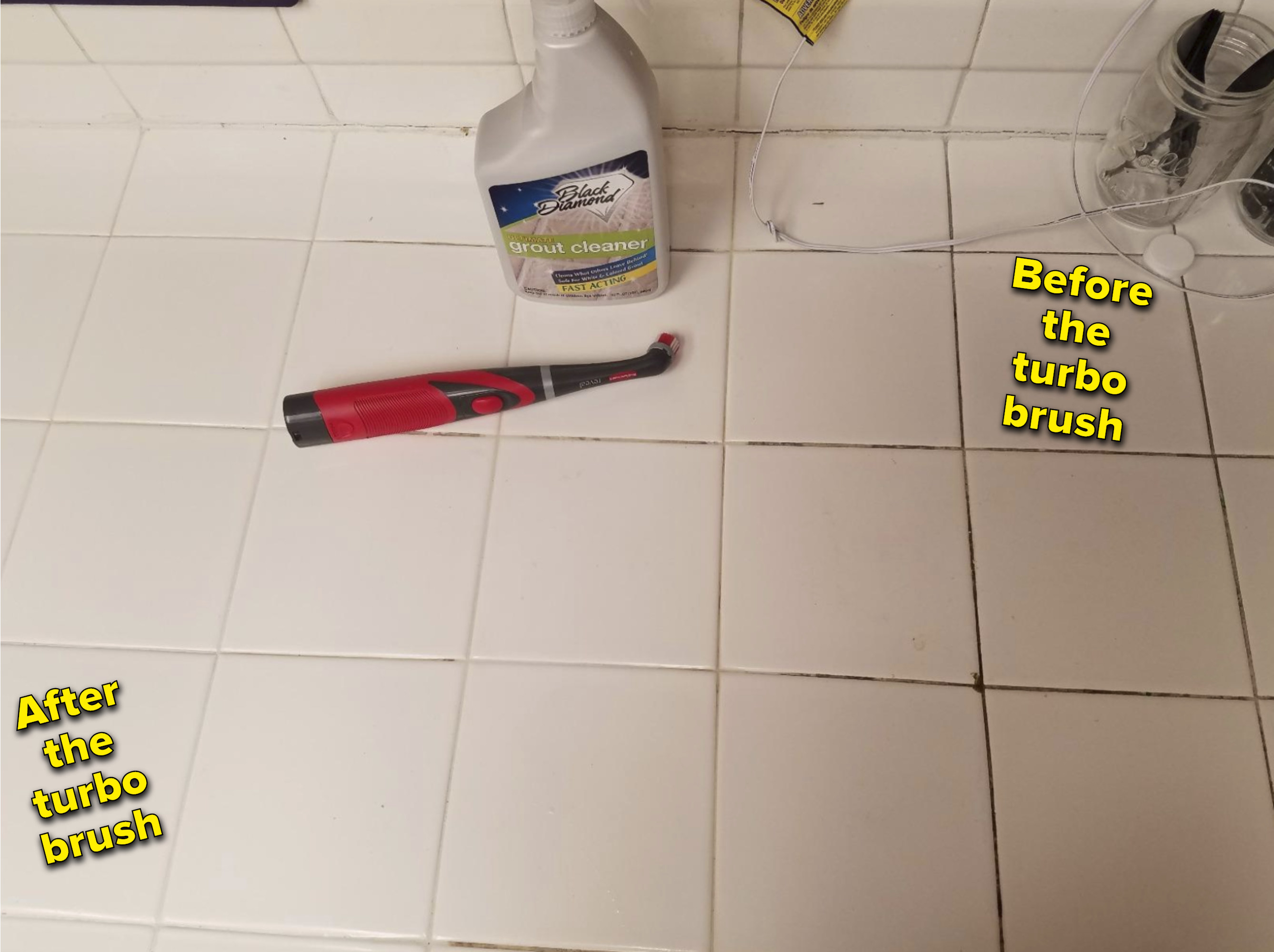 the brush laying on the floor. one side of the tiled floor is completely white after using the brush. The right side of the floor still has black grime in the crevices of the tile.