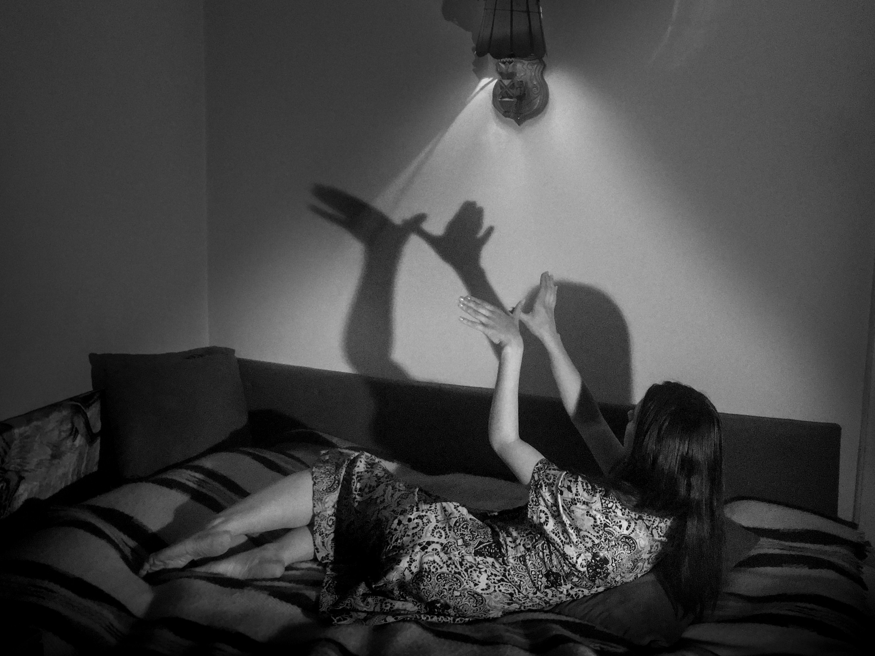 A woman makes shadow puppets of birds from her couch