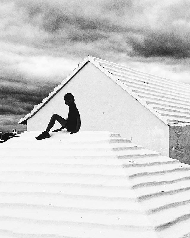 A child in silhouette sites on a roof